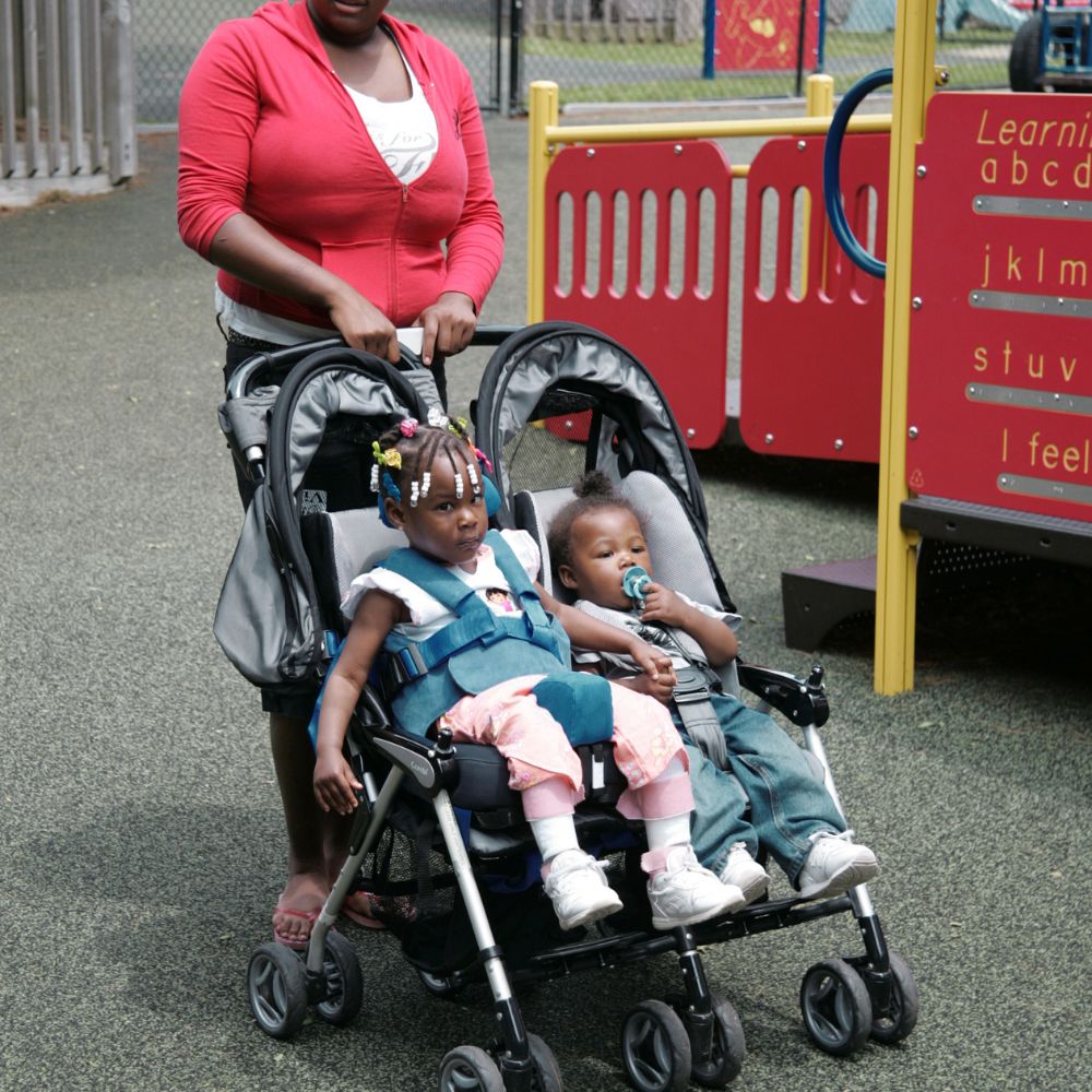 Caregiver Pushing Toddlers In Double Stroller